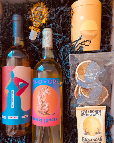 This box includes Vinovore Between Us wine, Vinovore Safari Sunset wine, P. F. Candle Co. Golden Hour candle, Crispy Dark Chocolate Orange Slices, Wild Yonder Botanical Bath Salts & Body Scrub (choose one pack) and an Acrylic Wine Stopper (choose one color).