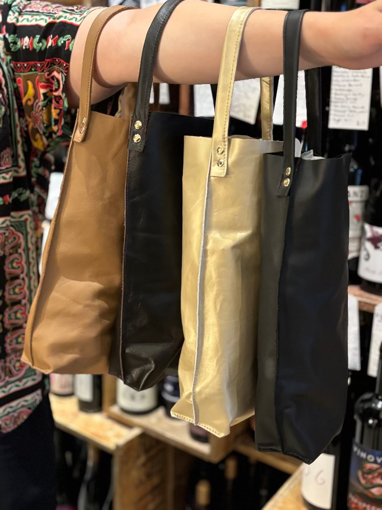 Four bags in different colors hanging on a rack with a blurred background.