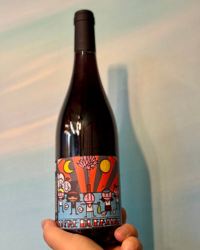 Wine bottle with a colorful label held against a neutral background
