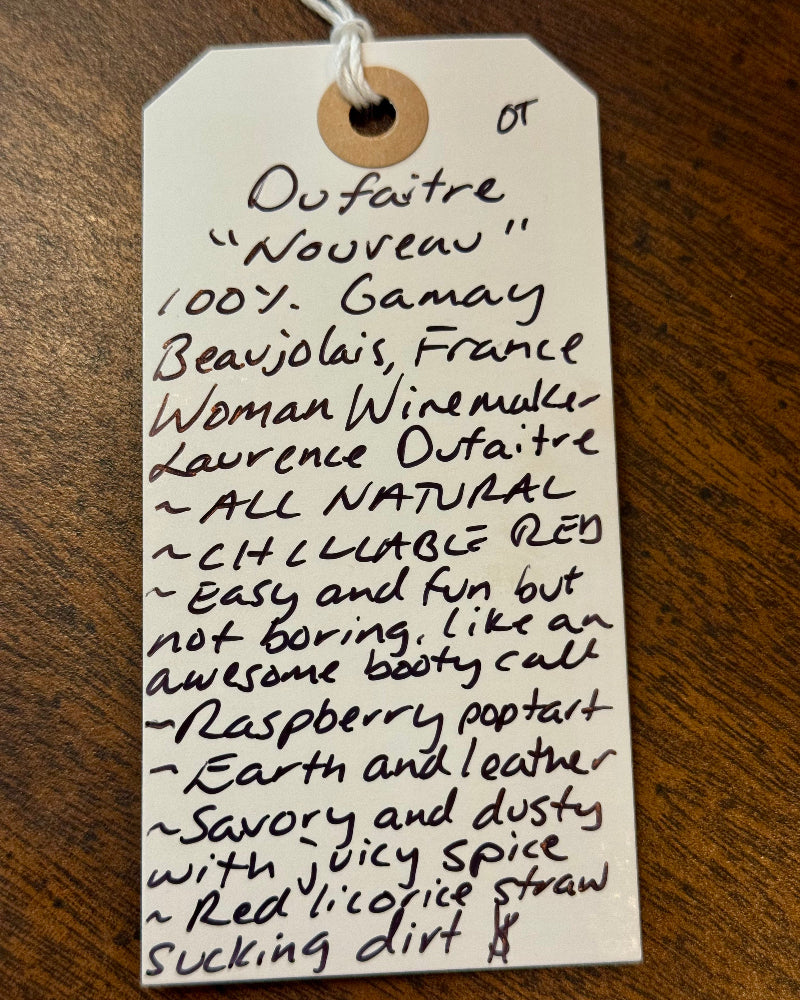 Handwritten tag on a wooden surface with wine description text.