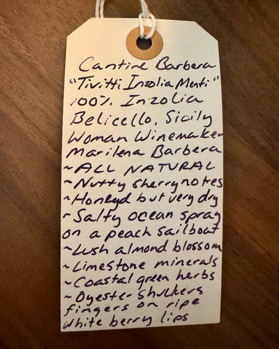 Handwritten tag with wine description on a wooden surface