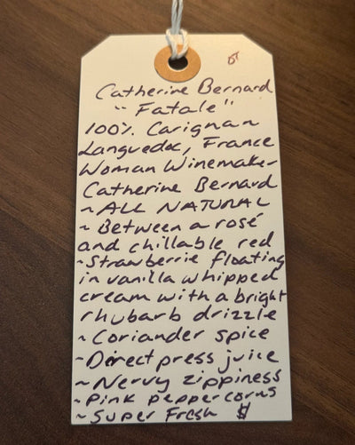 Handwritten tag with wine description on a wooden surface