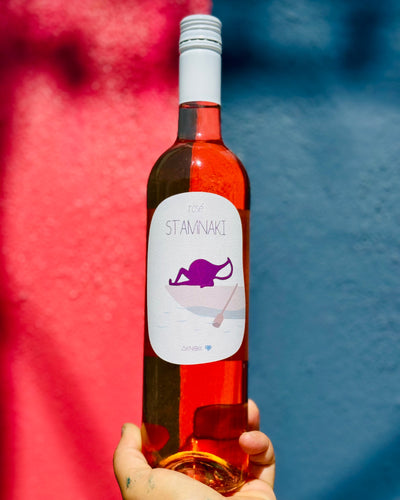 Bottle of Stavrinaki wine held against a colorful background