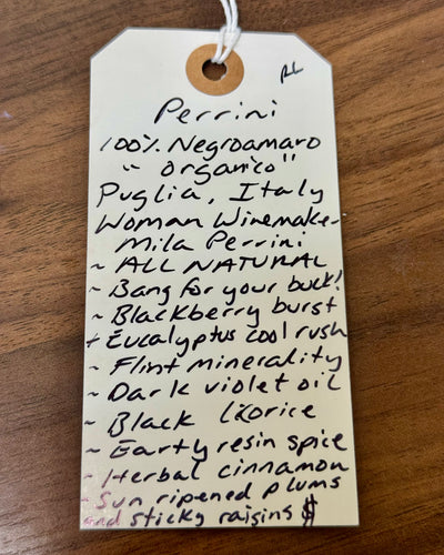 Handwritten tag with wine description on a wooden surface
