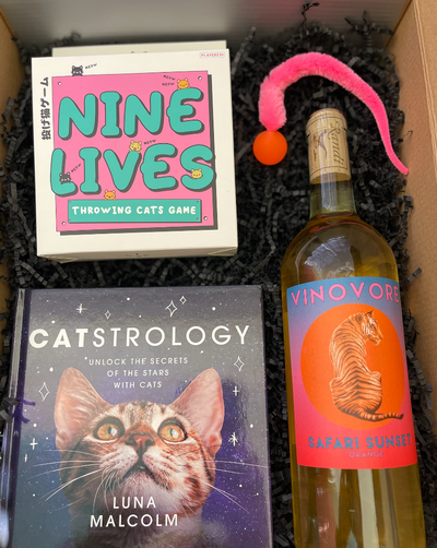 This box includes Vinovore Safari Sunset wine, Desi and Roo Wiggly Cat Toy (colors will vary), Nine Lives Throwing Cats game and Catstrology book.