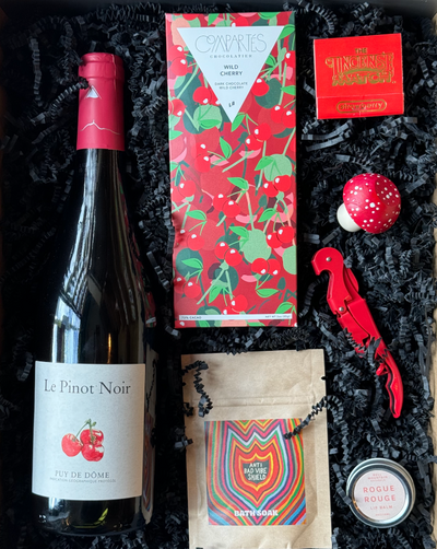 This box includes a bottle of wine, Compartés chocolate bar, a pack of incense matches, a mushroom bottle stopper, corkscrew wine opener, lip balm and bath soak.