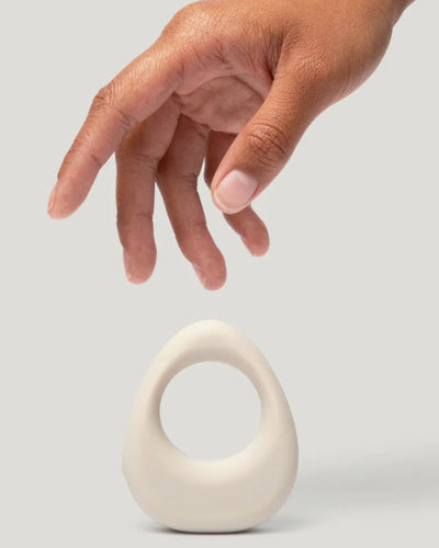 Hand reaching towards a white ceramic object on a light gray background