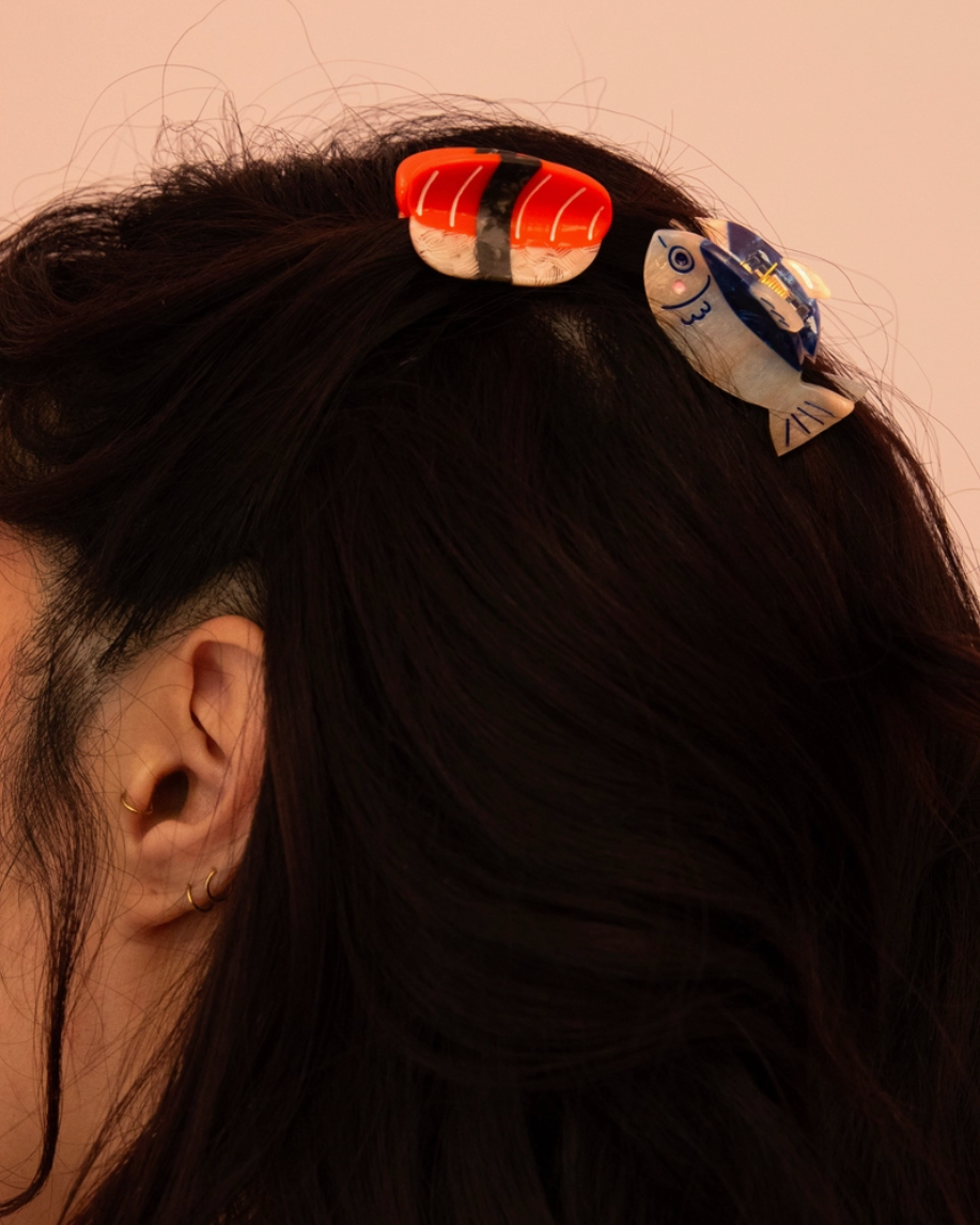 Person wearing sushi-themed hair clips on a plain background
