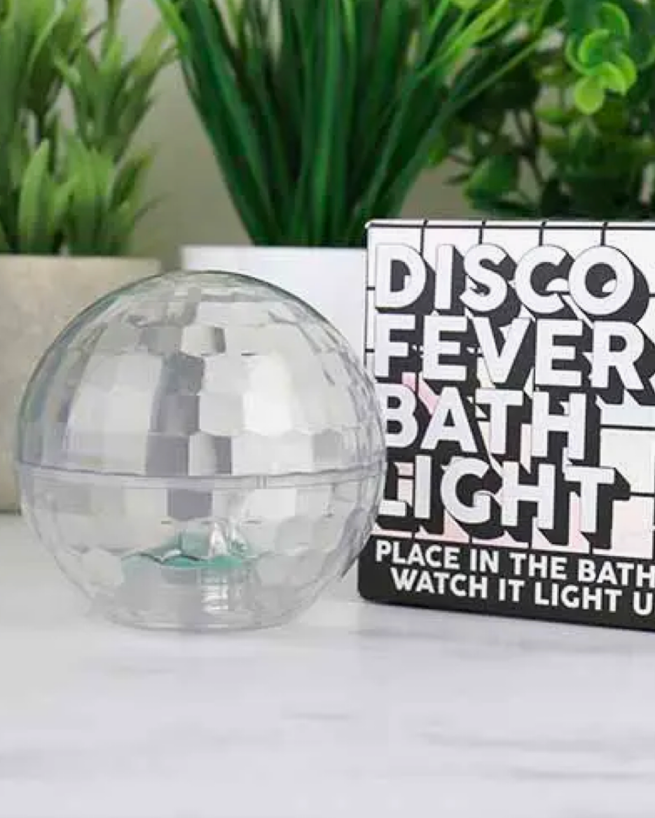 Discoball with packaging labeled 'Disco Fever Bath Light' on a white surface with plants in the background.