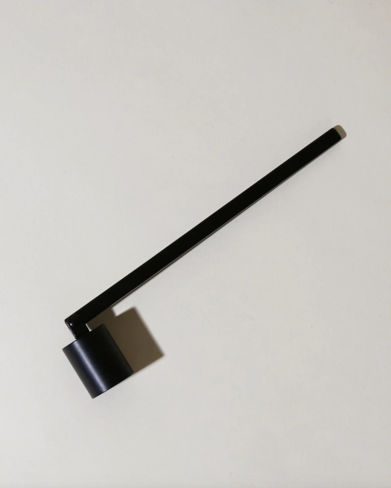 Black candle snuffer with a long arm on a light gray background