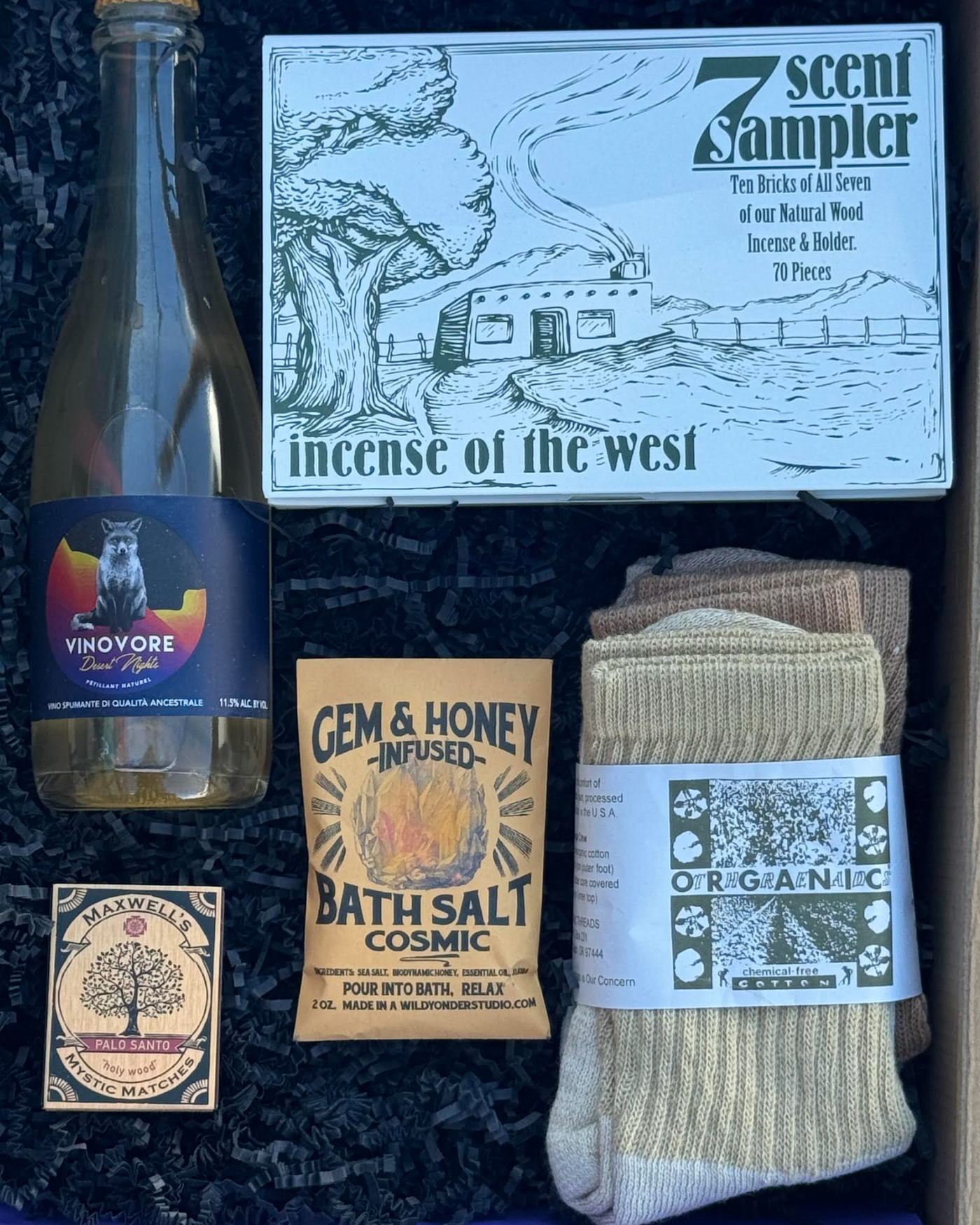 Collection of items including a bottle, socks, bath salt, and a box labeled 'Incense of the West' on a dark background.