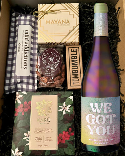 This box includes Mayana 4 Piece Truffle box, Q's Nuts Mexican Chocolate Almonds, Oregon Bark Tom Bumble, Karü Chocolates 70% Cacao with Coffee, Mild Addictions Coconut and a bottle of wine. You choose what color your want, and we'll pop in the perfect bottle to complement this box.