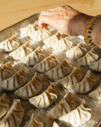 Every week, Mama Fong comes into Woon to make hundreds of pork and veggie dumplings. They call them “Mama Fong’s Fortunate Frozen Dumplings”. In Chinese, the number “8” sounds like the word for “fortune. So, we sell 8 dumplings with an 8 ball sticker, all for good fortune.